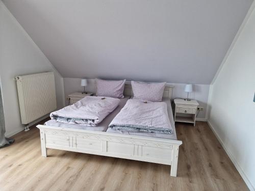 ein weißes Schlafzimmer mit 2 Betten und 2 Nachttischen in der Unterkunft Ferienwohnung An der Karlskuppe in Eisenach