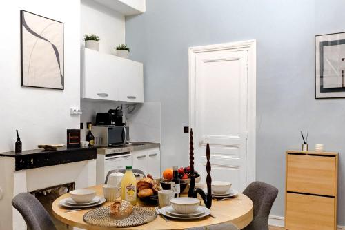une cuisine avec une table en bois entourée de chaises. dans l'établissement Charme Parisien Studio Cosy pour 4 Personnes, à Paris