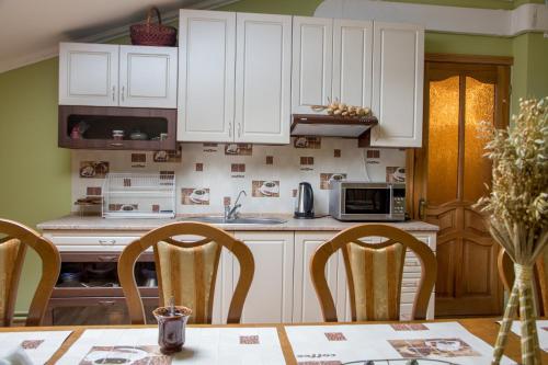 a kitchen with white cabinets and a table with chairs at Lions Heart Hostel in Lviv