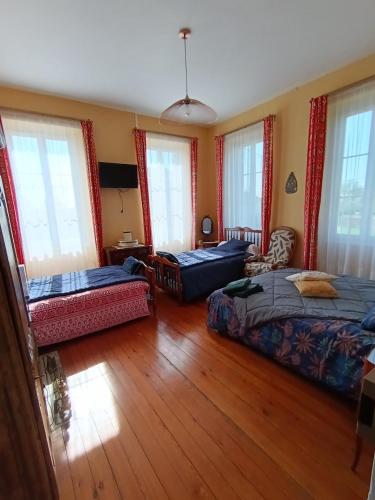 une chambre avec deux lits et un canapé et des fenêtres dans l'établissement Gîte La Burthe, à Monprimblanc