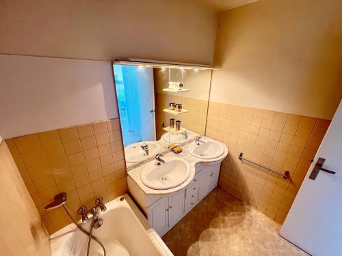 une salle de bain avec deux lavabos, une baignoire et un miroir dans l'établissement Charming seaside apartment, à Cannes