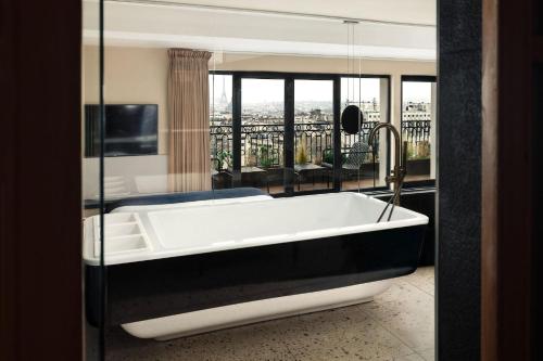 a bath tub in a room with a balcony at Terrass" Hotel in Paris