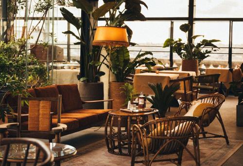 a room with a couch and tables and potted plants at Terrass" Hotel in Paris