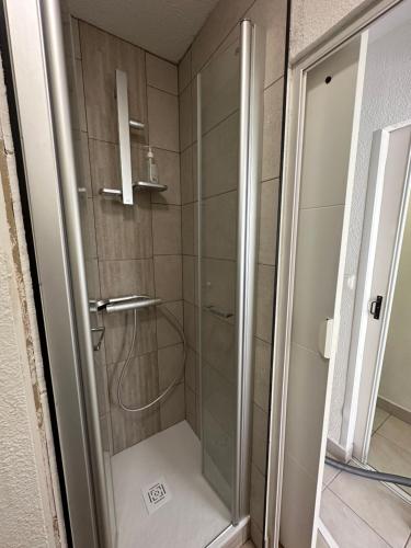 une douche avec une porte vitrée dans une salle de bain dans l'établissement Appartement proche de la plage, à Saint Pierre La Mer