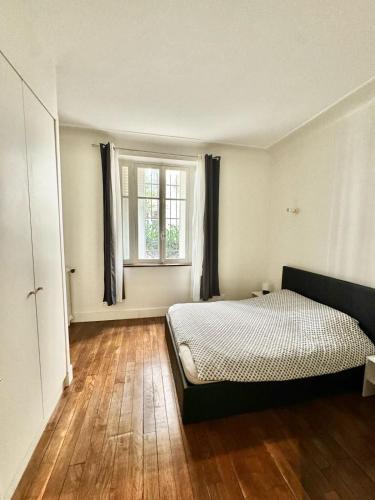 une chambre avec un lit et une fenêtre dans l'établissement Appartements Auteuil Paris 16, à Paris