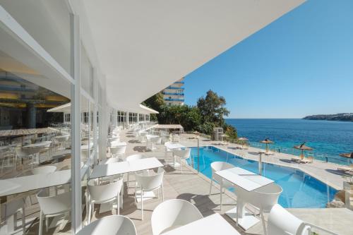 een rij witte tafels en stoelen naast een zwembad bij Bahia Principe Sunlight Coral Playa - Adults Only in Magaluf
