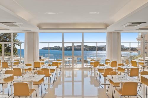 een eetkamer met tafels en stoelen en grote ramen bij Bahia Principe Sunlight Coral Playa - Adults Only in Magaluf
