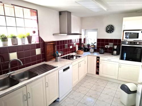 une cuisine avec des armoires blanches et un évier dans l'établissement Chambre d'hotes au coeur du village, à Reichshoffen