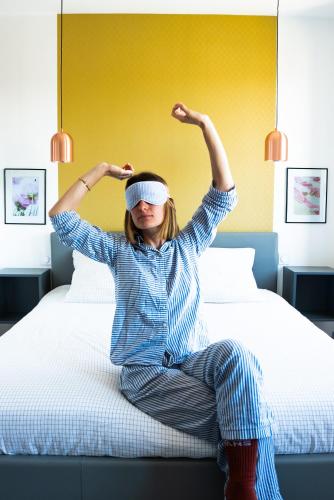 a woman sitting on a bed with her arms in the air at Villa Bel-Amy in Saint-Pair-sur-Mer
