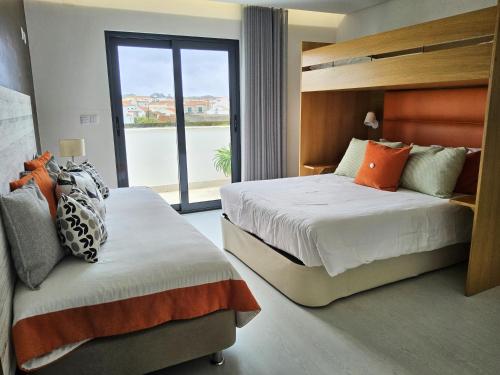 a hotel room with two beds and a large window at Bica, luxury heated penthouse with jacuzzi and large terrace in Baleal in Baleal
