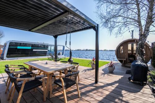 a patio with a table and chairs and a boat at Villa Perla Mare - Sauna Experience - On a lake near Amsterdam in Vinkeveen
