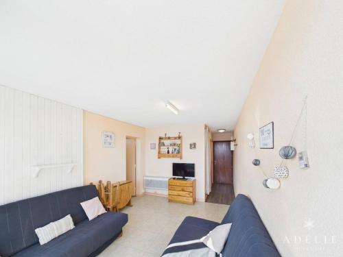 un salon avec un canapé bleu et une télévision dans l'établissement Studio confortable au centre, proche remontées mécaniques - FR-1-398-573, à Montvalezan