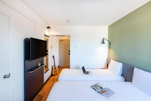 a hotel room with two beds and a tv at Hotel ibis Evora in Évora