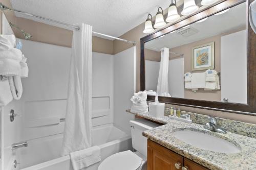 a bathroom with a sink and a toilet and a mirror at The Strand - A Boutique Resort in Myrtle Beach