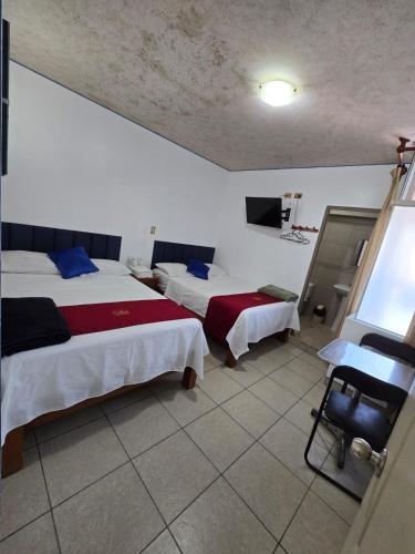 a hotel room with two beds and a television at Hotel los angeles in Huaral