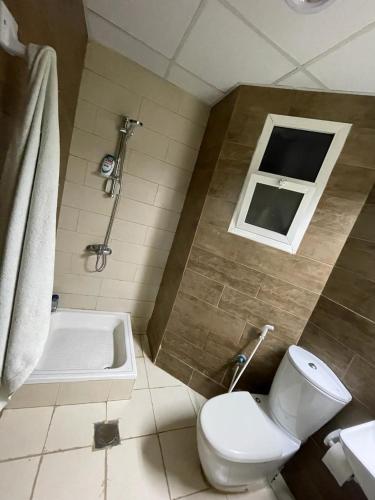 un bagno con wc, doccia e finestra di Private Condo ad Ajman