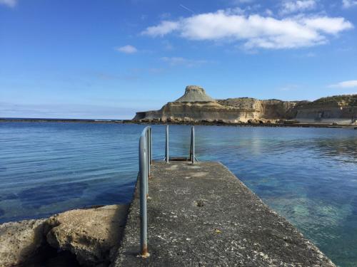 a pier in the water with a mountain in the background at Dar tal-Kaptan Boutique Maison in Għasri