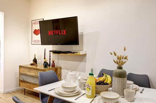 d'une salle à manger avec une table et une télévision murale. dans l'établissement Confort et calme pour 6 pers a Levallois-Perret, à Levallois-Perret