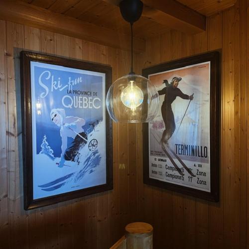 two posters on a wall with a light and a lamp at Chalet El Nido Nendaz in Iserables
