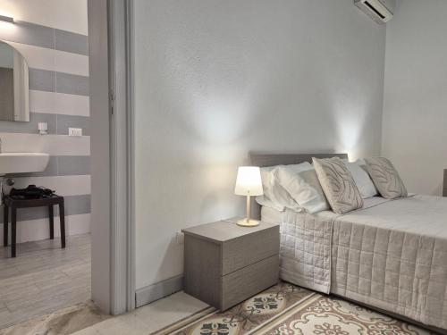 a bedroom with a bed and a table with a lamp at La Mattanza in Trapani