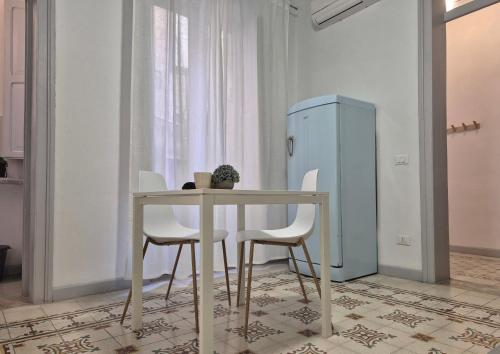 a table with white chairs and a blue refrigerator at La Mattanza in Trapani