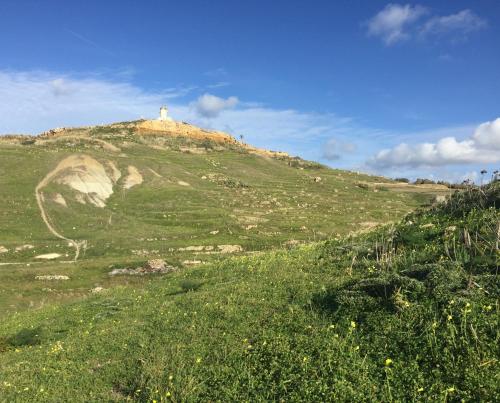 a hill with a lighthouse on top of it at Dar tal-Kaptan Boutique Maison in Għasri