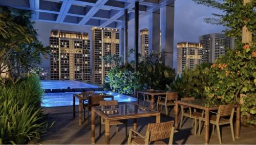 a patio with tables and chairs and a pool at Revo Aurora Home at Pavilion Bukit Jalil in Kuala Lumpur