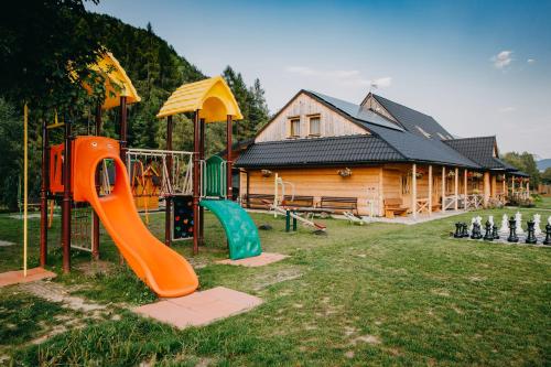 a playground in front of a log house at Pensjonat Jurkowski Wellness & Spa in Ochotnica Dolna