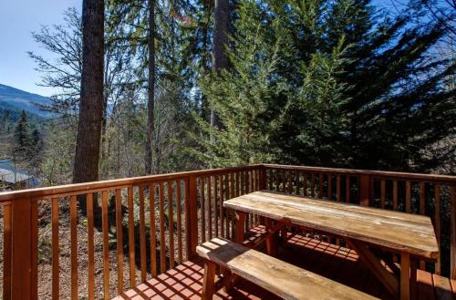 a wooden bench sitting on a wooden deck with trees at Mt Baker Rim Cabin 44 - A Cozy Rustic Cabin With Modern Charm in Glacier