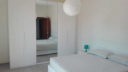 Habitación blanca con cama y espejo en Appartamento Sezzate 40, en Strada