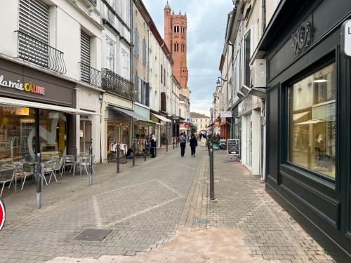 eine Straße mit Geschäften und Menschen, die die Straße hinuntergehen in der Unterkunft Studio confortable avec balcon in Villeneuve-sur-Lot