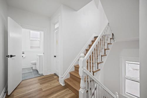 a white staircase in a home with white walls and wood floors at Shadyside, Pittsburgh !H Modern and Bright Private Bedroom with Shared Bathroom in Pittsburgh