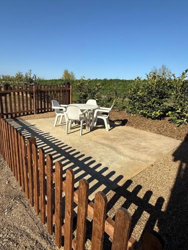 a patio with a table and chairs next to a fence at The Lodge in Prickwillow