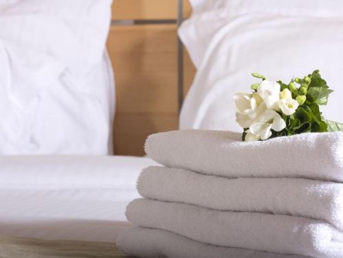 a pile of towels on a bed with a bouquet of flowers at JUMA alpine living in Flachau