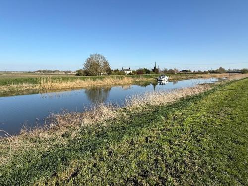 a river with a boat in the middle of a field at The Lodge in Prickwillow