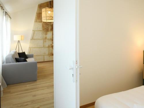 une chambre avec un lit blanc et un canapé dans l'établissement L'élégant, T2 avec climatisation, wifi, à Cognac