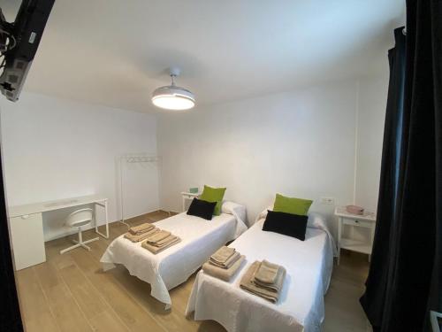 a room with two beds and a desk in it at Apartmento Carmen Viejo, Centro in Sanlúcar de Barrameda