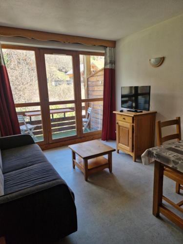 un salon avec un canapé et une télévision dans l'établissement Appartement F2 au pied des pistes, à Valloire