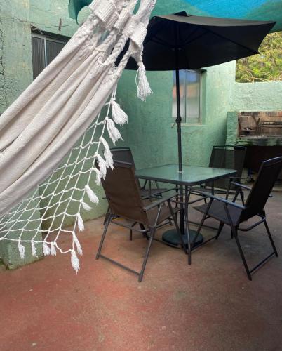 a table with chairs and an umbrella on a patio at Casa rosa - se reserva con seña in Barra del Chuy