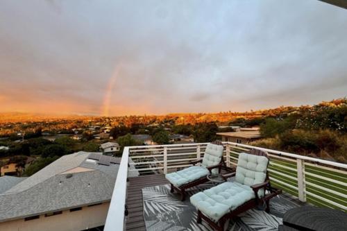 a balcony with two chairs and a rainbow in the sky at Waikoloa Views in Waikoloa Village