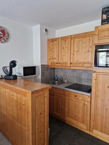 une cuisine avec des armoires en bois et un évier dans l'établissement Appartement F2 au pied des pistes, à Valloire