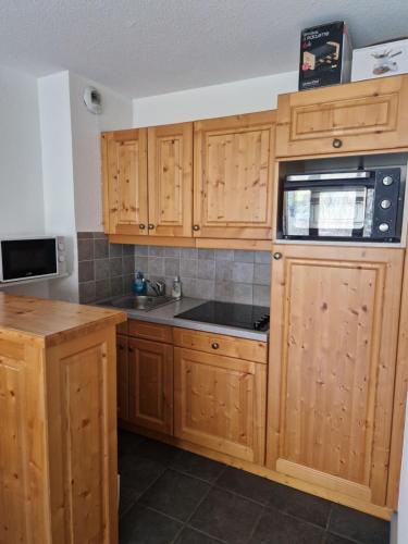 une cuisine avec des armoires en bois et un évier dans l'établissement Appartement F2 au pied des pistes, à Valloire