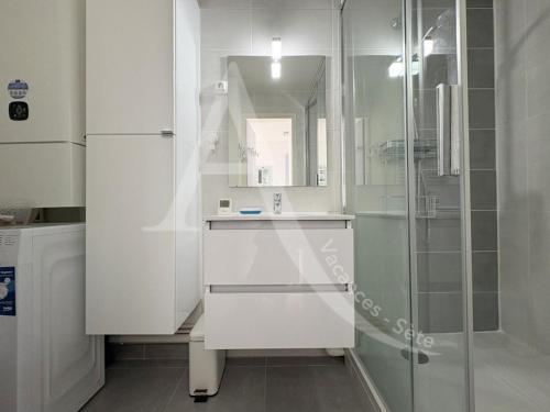 une salle de bain blanche avec une douche et un lavabo dans l'établissement APPARTEMENT 1 CHAMBRE BORD DE MER, à Sète