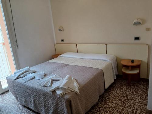 a hotel room with a bed with clothes on it at Hotel Golino in Rimini