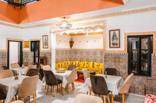 a restaurant with tables and chairs and a yellow couch at Riad GALFANE in Marrakech