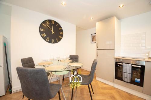 a dining room with a table and a clock on the wall at Queen Street Stay - SJA Stays - Modern 2 Bed Apartment in Peterhead