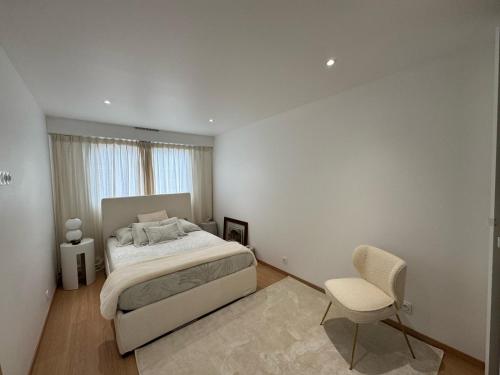 une chambre blanche avec un lit et une chaise dans l'établissement vue mer, à Vallauris