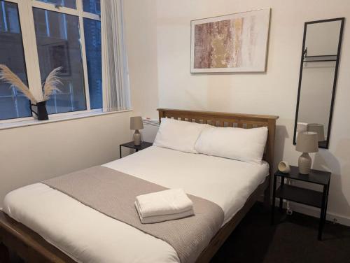 ニューカッスル・アポン・タインにある3 Bed Executive Apartmentの白いシーツと窓のあるベッドのある寝室