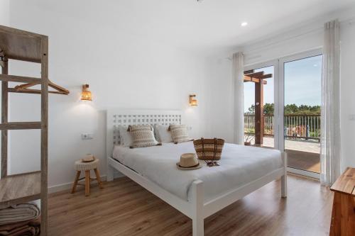 a white bedroom with a bed with a hat on it at Quinta dos Raposos- Nazaré Portugal in Nazaré