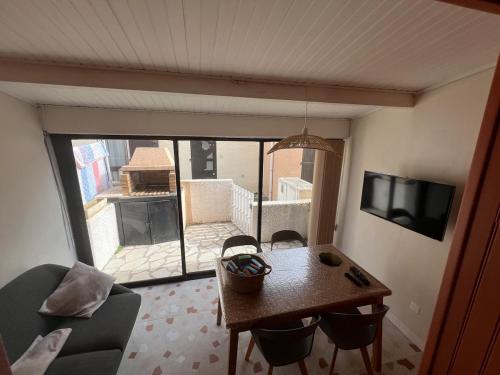 a living room with a table and chairs and a television at Maison Terracotta des Karantes in Narbonne-Plage